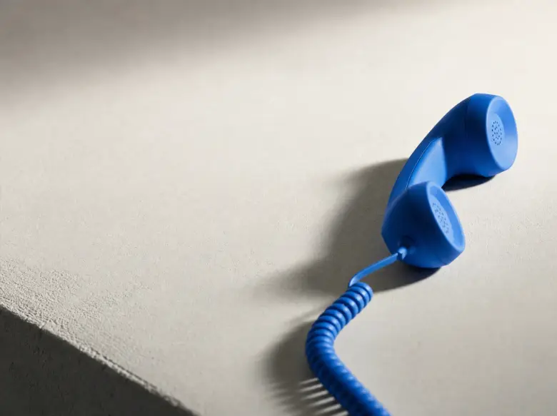 A vivid blue telephone receiver resting in warm daylight